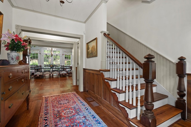 staircase featuring an inviting chandelier, dark parquet flooring, and ornamental molding