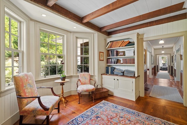 sitting room with beamed ceiling, wood-type flooring, and built in shelves