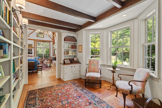 living area featuring an inviting chandelier, light hardwood / wood-style floors, and beam ceiling