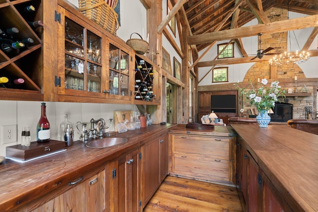 bar featuring butcher block counters, high vaulted ceiling, sink, beam ceiling, and light hardwood / wood-style flooring