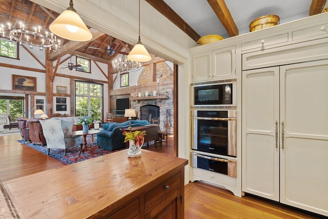 kitchen featuring plenty of natural light, a stone fireplace, light wood-type flooring, and black microwave