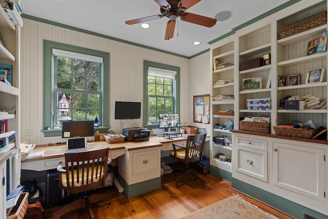 office featuring built in desk, light hardwood / wood-style flooring, a wealth of natural light, and ceiling fan