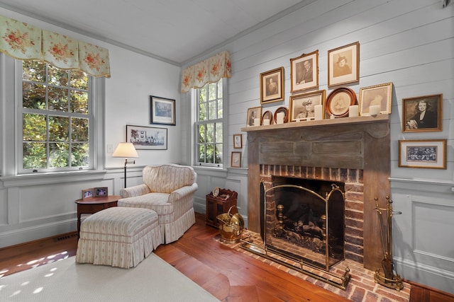 living area featuring a fireplace, wood-type flooring, and crown molding