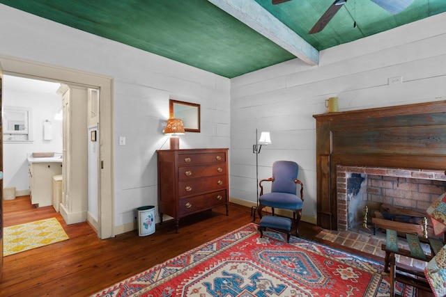 living area with a fireplace, beamed ceiling, ceiling fan, and wood-type flooring