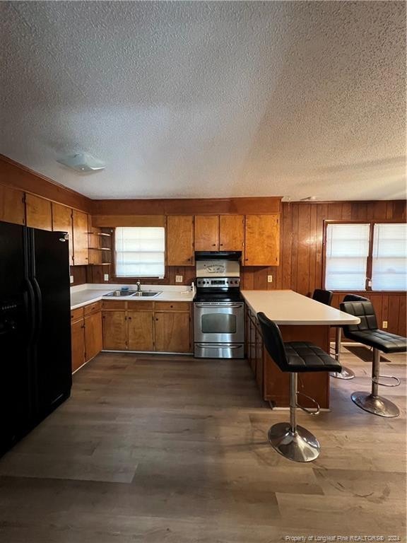 kitchen featuring dark hardwood / wood-style floors, stainless steel electric range, black fridge, and sink