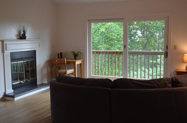 living room with a healthy amount of sunlight, a tiled fireplace, and light wood-type flooring