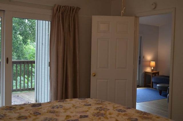 bedroom with wood-type flooring, access to outside, and multiple windows