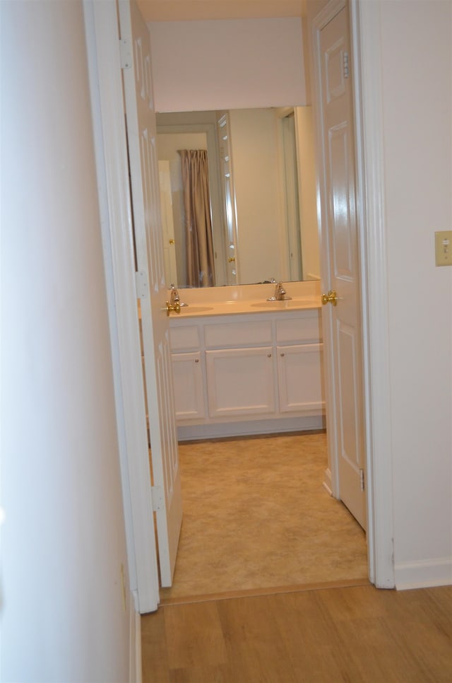 hallway featuring light carpet and sink