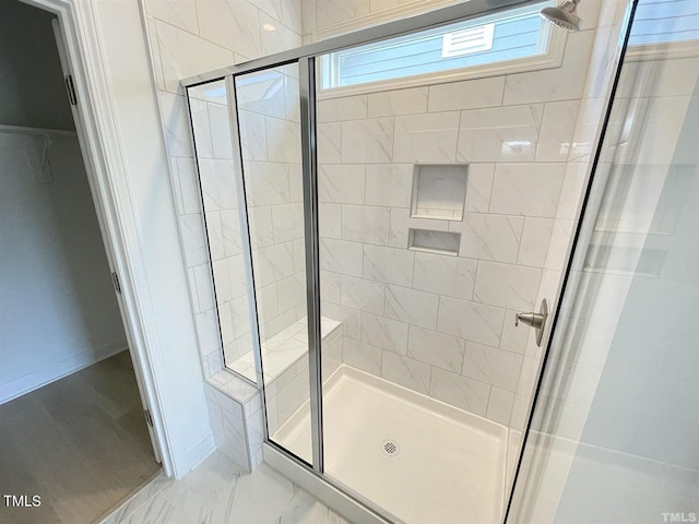 bathroom with marble finish floor, a stall shower, and baseboards