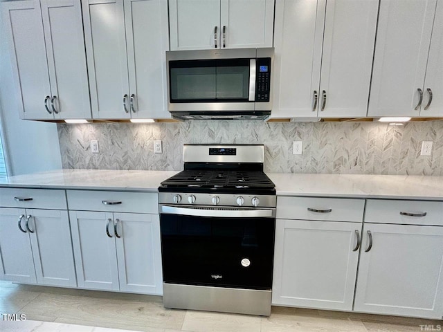 kitchen with stainless steel appliances, tasteful backsplash, and light stone countertops