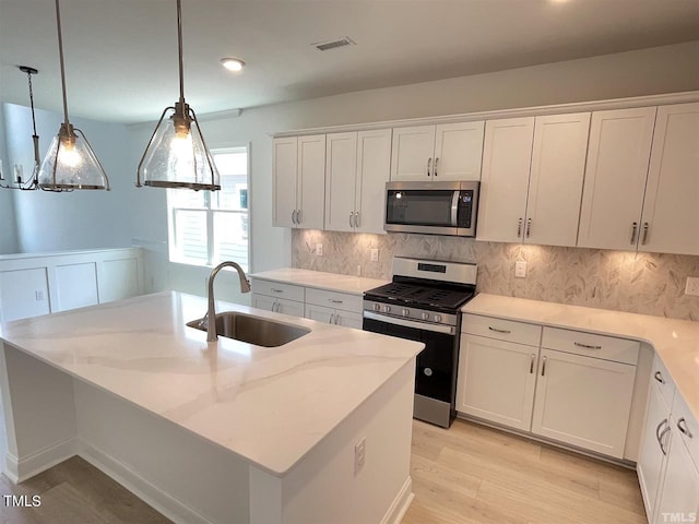 kitchen featuring visible vents, white cabinets, decorative backsplash, stainless steel appliances, and a sink