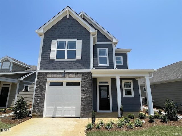 craftsman-style house with concrete driveway, stone siding, a porch, and an attached garage