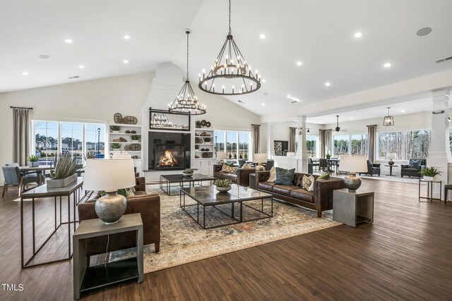 living area with a healthy amount of sunlight, ornate columns, a fireplace, and wood finished floors