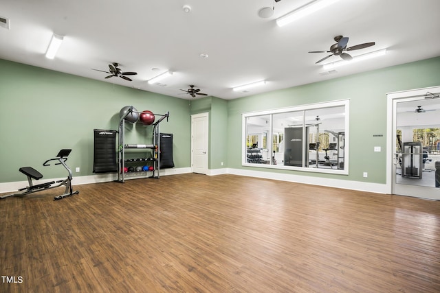 workout area featuring a ceiling fan, visible vents, baseboards, and wood finished floors