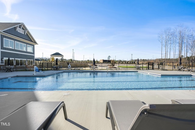 community pool with a patio area and fence