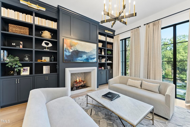 living room featuring built in features, a notable chandelier, and light hardwood / wood-style flooring