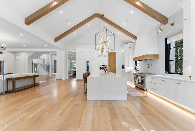 kitchen with pendant lighting, premium range hood, appliances with stainless steel finishes, white cabinets, and light stone counters