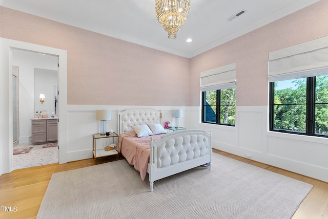 bedroom with connected bathroom, a chandelier, and light wood-type flooring