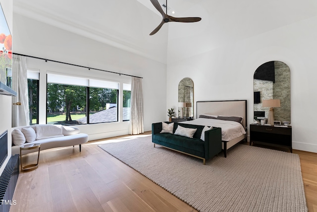 bedroom with a towering ceiling, ceiling fan, and light wood-type flooring