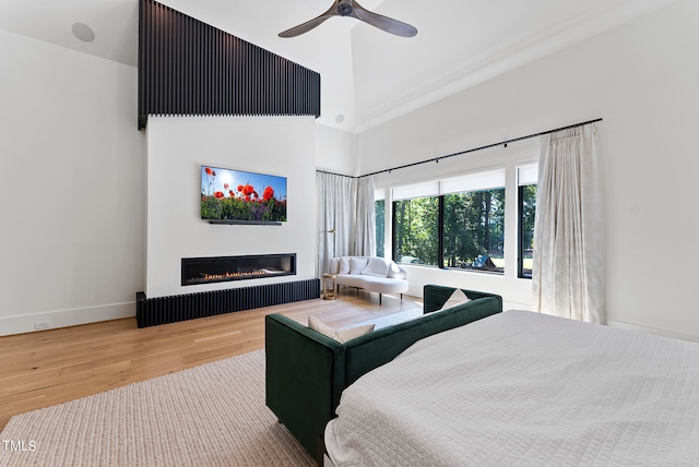 bedroom featuring ceiling fan, a towering ceiling, and light wood-type flooring