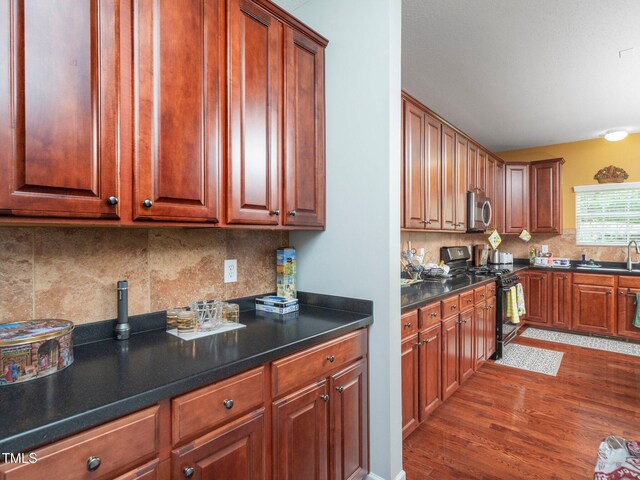 1209 Partington St, Wake Forest, NC 27587 - kitchen with stainless steel microwave, black range with gas stovetop, dark wood finished floors, decorative backsplash, and dark countertops