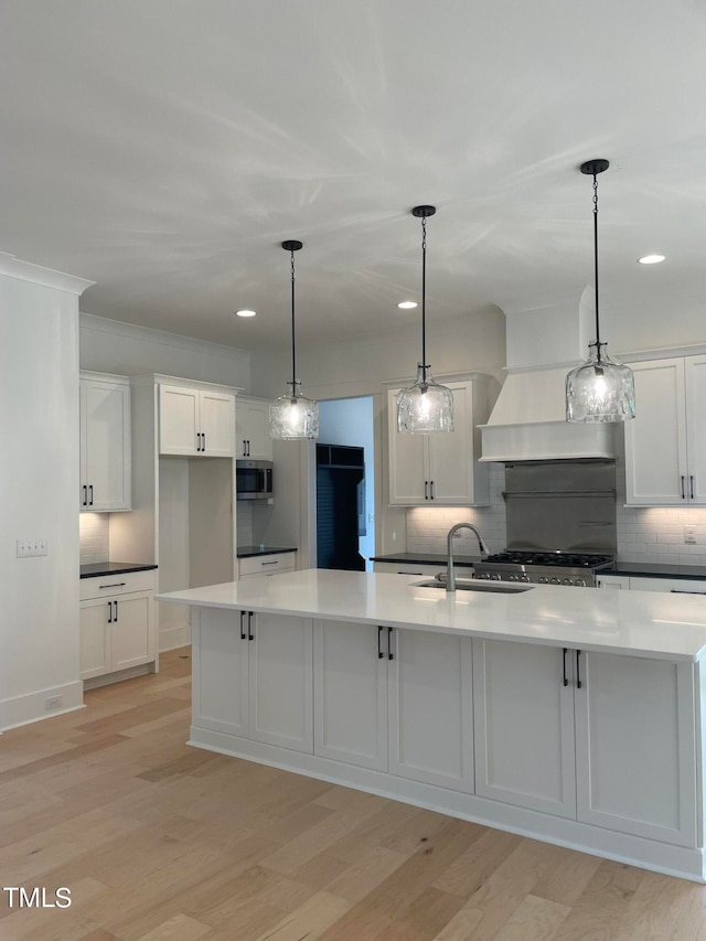 kitchen with pendant lighting, white cabinets, sink, light hardwood / wood-style flooring, and stainless steel appliances