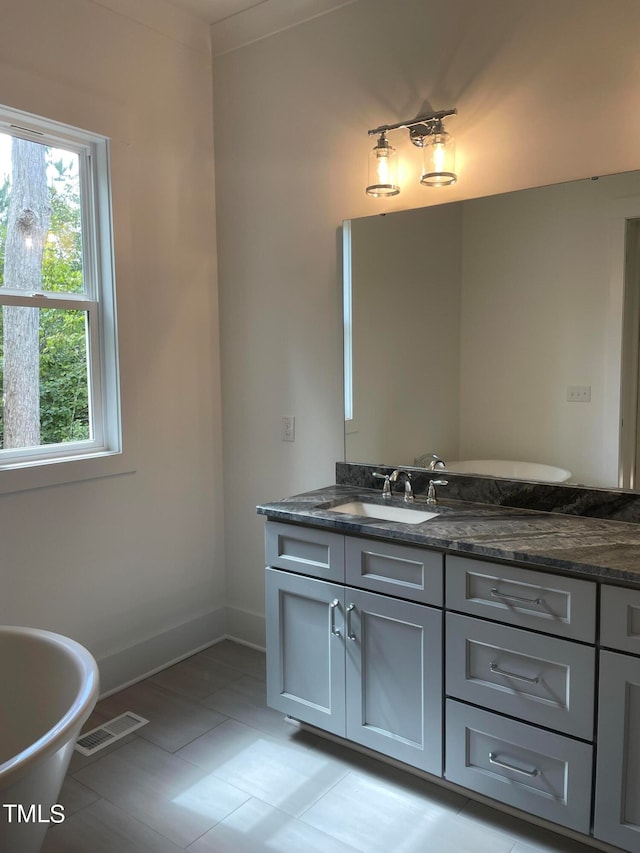 bathroom with tile patterned flooring, vanity, and a bathing tub