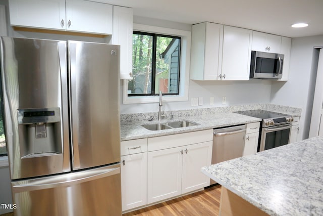 kitchen with light hardwood / wood-style flooring, appliances with stainless steel finishes, sink, and white cabinetry