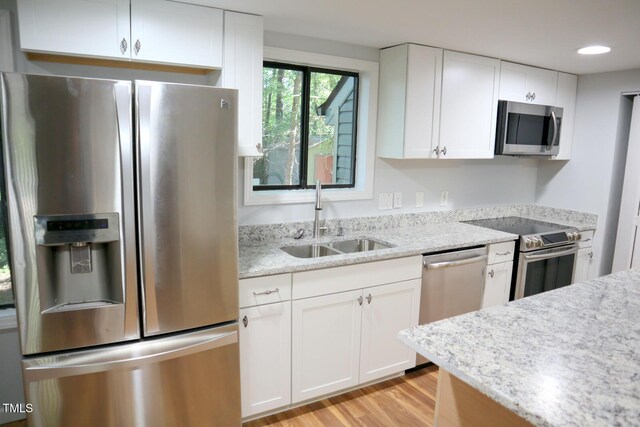 3404 Gemini Dr, Raleigh, NC 27604 - kitchen featuring stainless steel appliances, a sink, light wood-type flooring, white cabinetry, and light stone counters