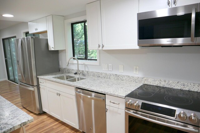 3404 Gemini Dr, Raleigh, NC 27604 - kitchen with light wood-style flooring, a sink, white cabinetry, and appliances with stainless steel finishes