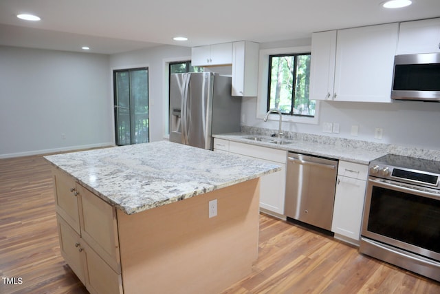 kitchen with sink, white cabinetry, a kitchen island, light hardwood / wood-style flooring, and appliances with stainless steel finishes