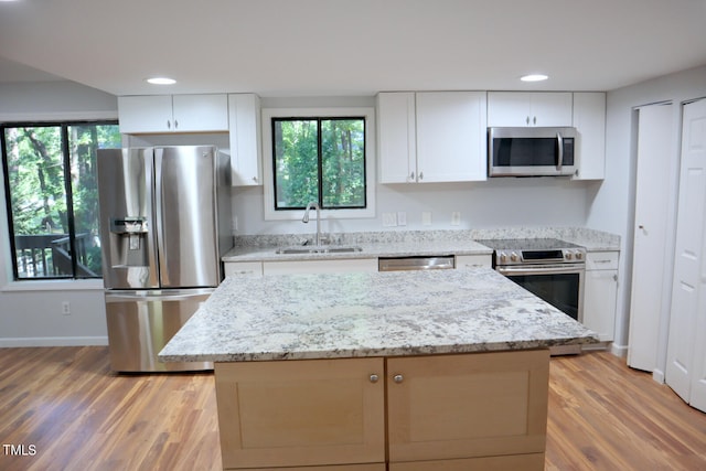 kitchen with appliances with stainless steel finishes, a center island, white cabinetry, and sink