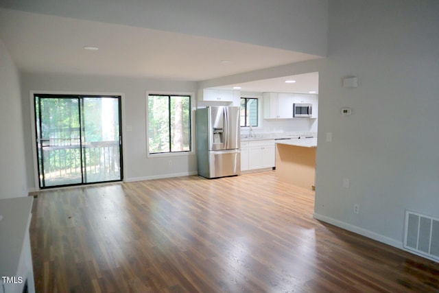 kitchen with appliances with stainless steel finishes, white cabinetry, and hardwood / wood-style floors