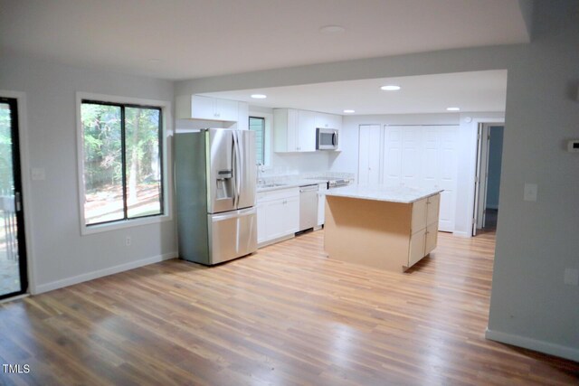 3404 Gemini Dr, Raleigh, NC 27604 - kitchen with light wood finished floors, white cabinets, baseboards, appliances with stainless steel finishes, and a kitchen island