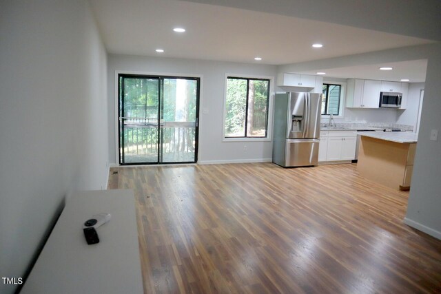 3404 Gemini Dr, Raleigh, NC 27604 - kitchen featuring white cabinets, light wood-type flooring, appliances with stainless steel finishes, and recessed lighting