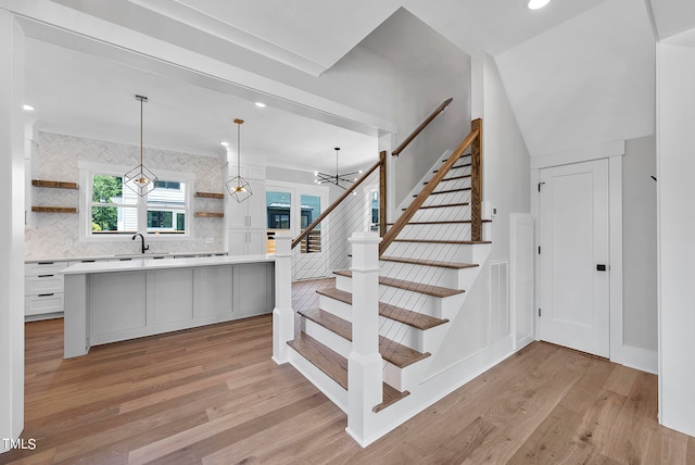 stairs featuring sink, light hardwood / wood-style flooring, and crown molding