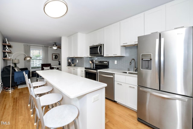 kitchen with a kitchen bar, sink, stainless steel appliances, and light hardwood / wood-style flooring