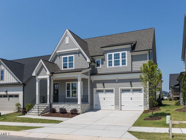 craftsman house with a garage, a front lawn, and covered porch