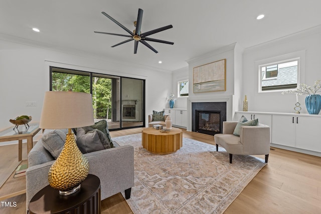 living room with ceiling fan, ornamental molding, plenty of natural light, and light hardwood / wood-style floors