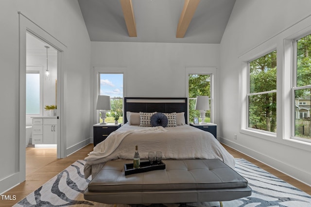 bedroom featuring multiple windows, lofted ceiling with beams, and ensuite bath