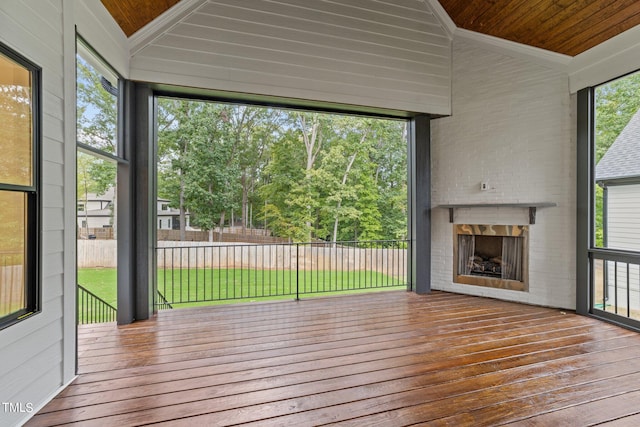 unfurnished sunroom featuring wood ceiling, a large fireplace, and a wealth of natural light