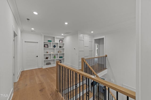 corridor with ornamental molding and light hardwood / wood-style flooring