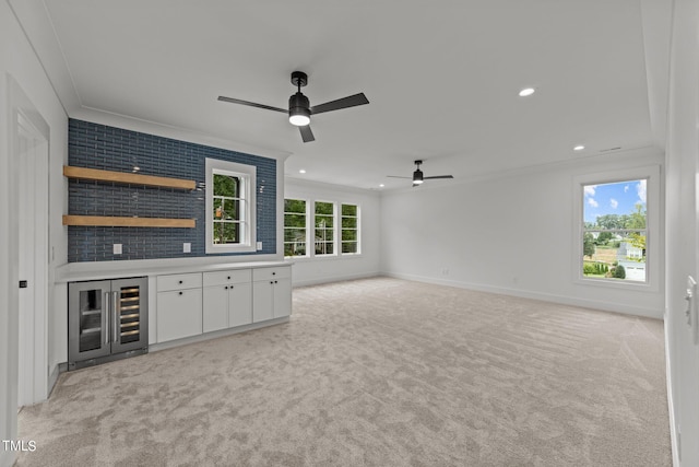 unfurnished living room with a healthy amount of sunlight, crown molding, light carpet, and ceiling fan