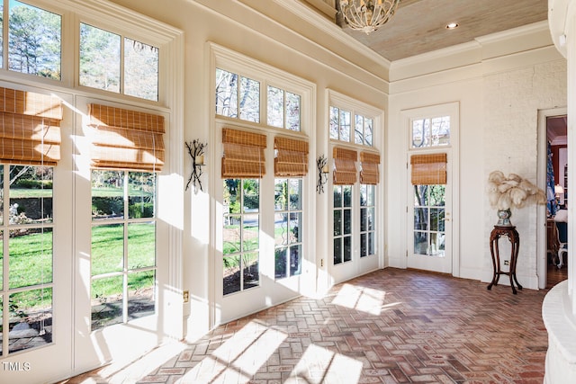 doorway to outside with ornamental molding, a healthy amount of sunlight, a chandelier, and a towering ceiling