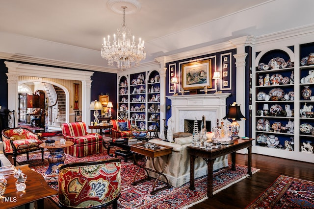 living room with dark hardwood / wood-style flooring, ornamental molding, a fireplace, ornate columns, and a notable chandelier