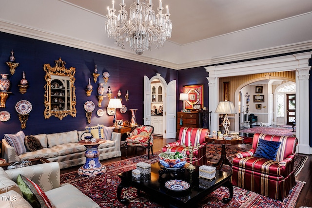 living room featuring dark hardwood / wood-style flooring, an inviting chandelier, crown molding, and decorative columns