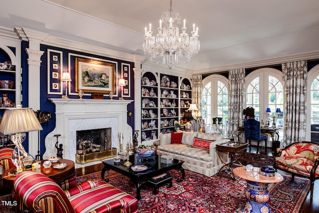 living room featuring crown molding, a notable chandelier, wood-type flooring, a high end fireplace, and decorative columns