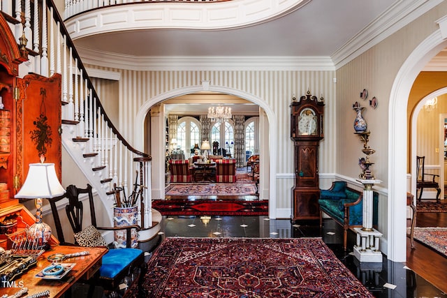 entryway featuring an inviting chandelier, dark wood-type flooring, and ornamental molding