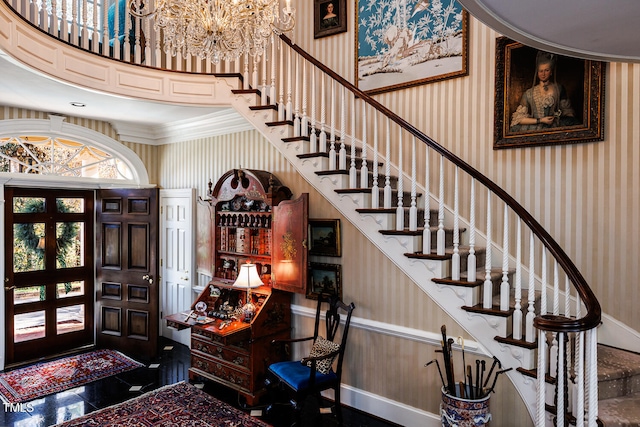 entrance foyer featuring crown molding, french doors, a chandelier, and a high ceiling