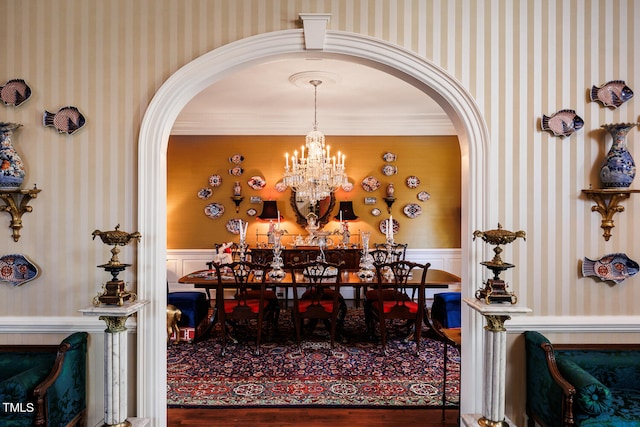 dining space with hardwood / wood-style floors, ornamental molding, and a chandelier